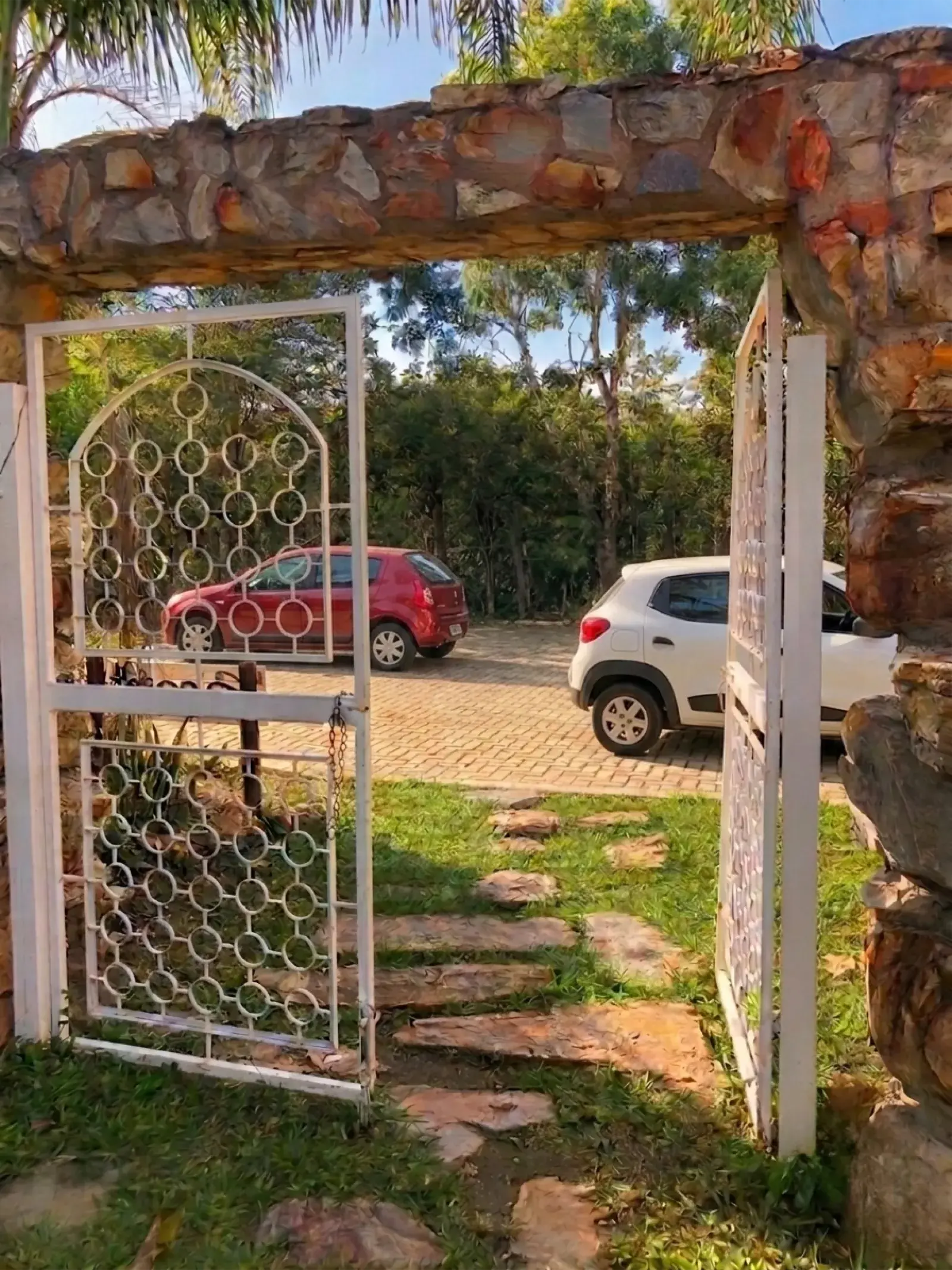 Portão de pedra com vista para o estacionamento da Shanti Pousada